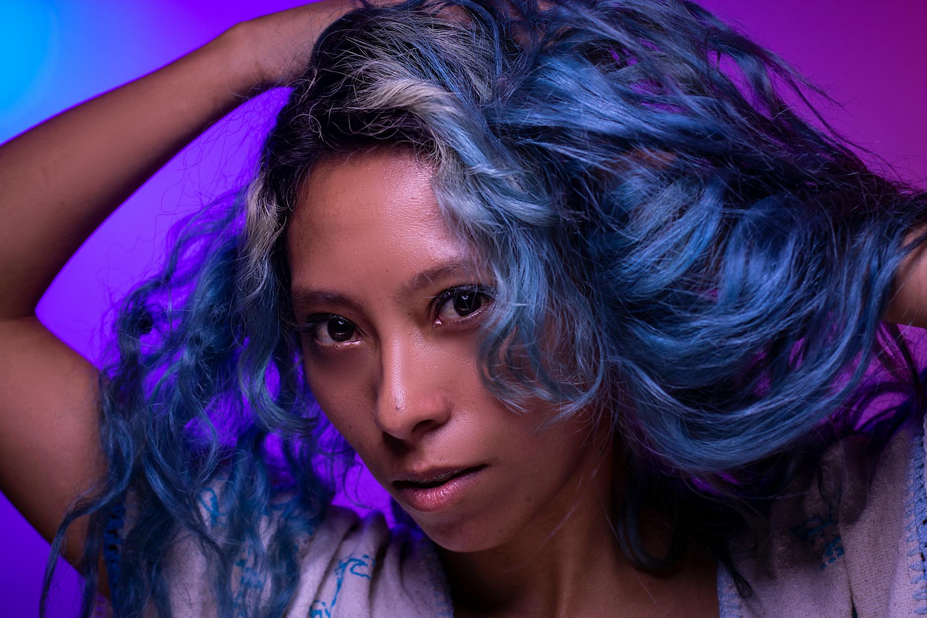 Elegante ritratto di una donna con vivaci capelli blu su sfondo viola.