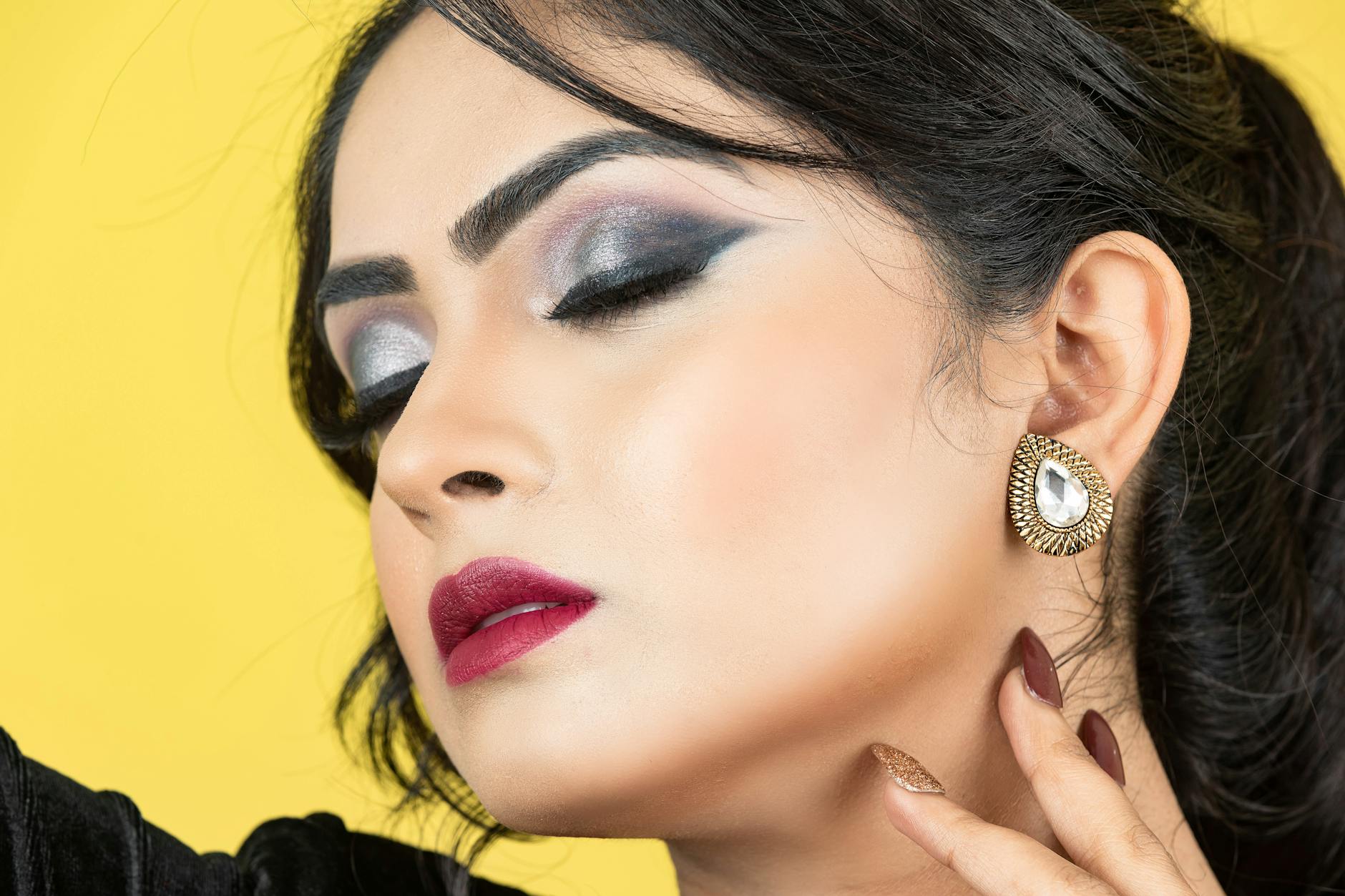 Splendido ritratto ravvicinato con trucco occhi audace ed eleganti gioielli, perfetto per temi di bellezza e moda.