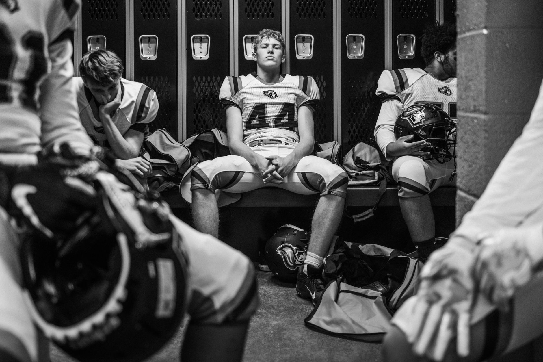 Intense black and white photo captures high school football players in a locker room pre-game.