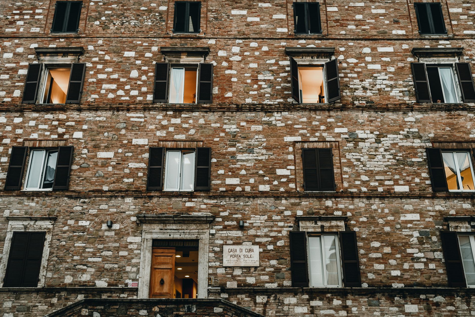 Low-angle view of an old brick façade in Perugia, Italy, showcasing traditional architecture.